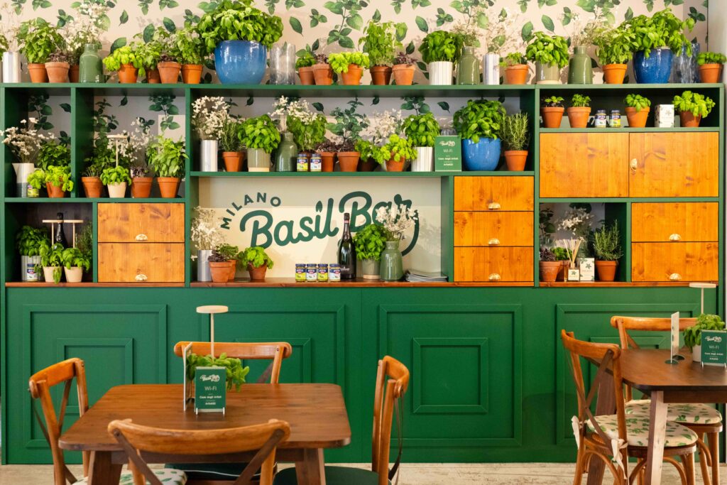 Basil Bar 10 Vista della sala interna del Basil Bar, con logo, parete, tavoli e sedie