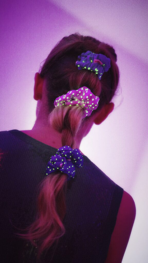 Weegle 6 Ragazza con i capelli intrecciati da elastici fosforescenti Weegle in una stanza con luce viola